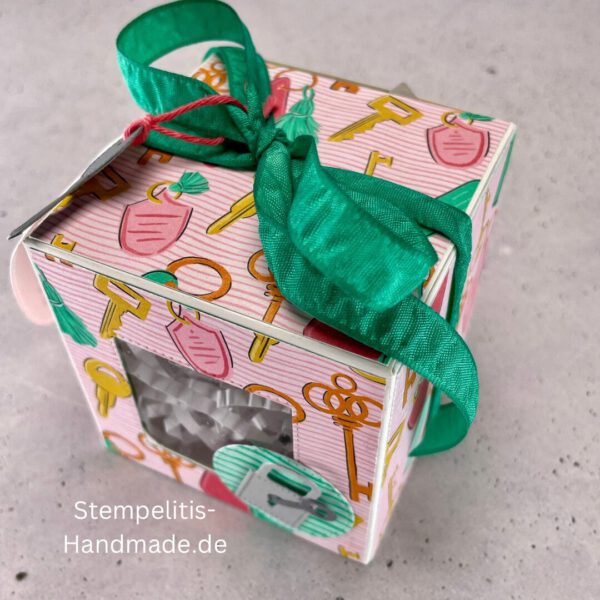 handdekorierte Fensterschachtel mit Glückwunsch-Anhänger, Geschenkbox mit Schlüsselmotiv und grünem Band, Nahaufnahme Fenster der Schachtel mit Füllung, runder Anhänger mit Schloss und Schlüssel, Schachtel geöffnet mit sichtbarem Inhalt, Glückwunsch-Tag an Geschenkbox, Geschenkverpackung für Einzug oder Prüfung